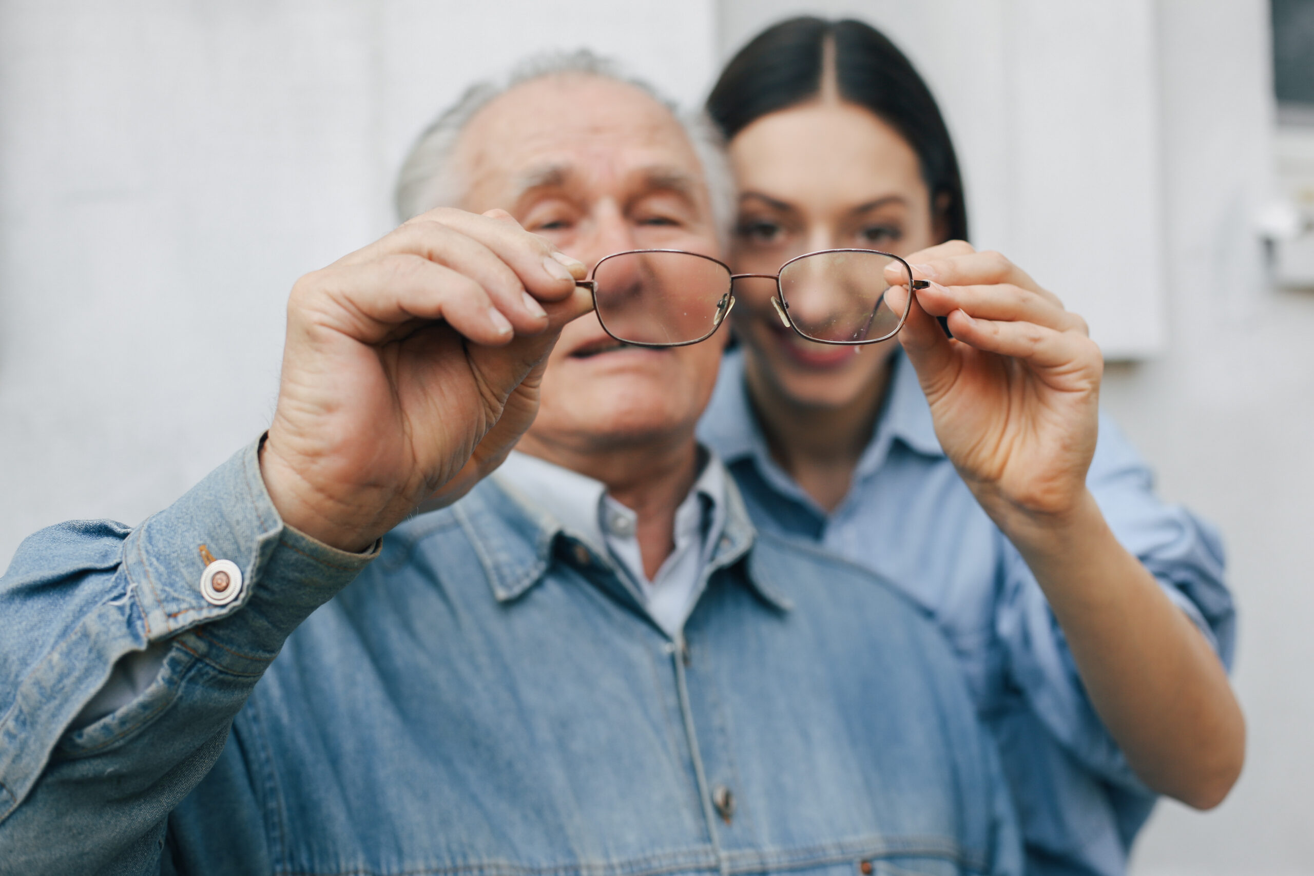 Grandfather on a gray background. Old man with granddaughter. Senior in a blue shirt.