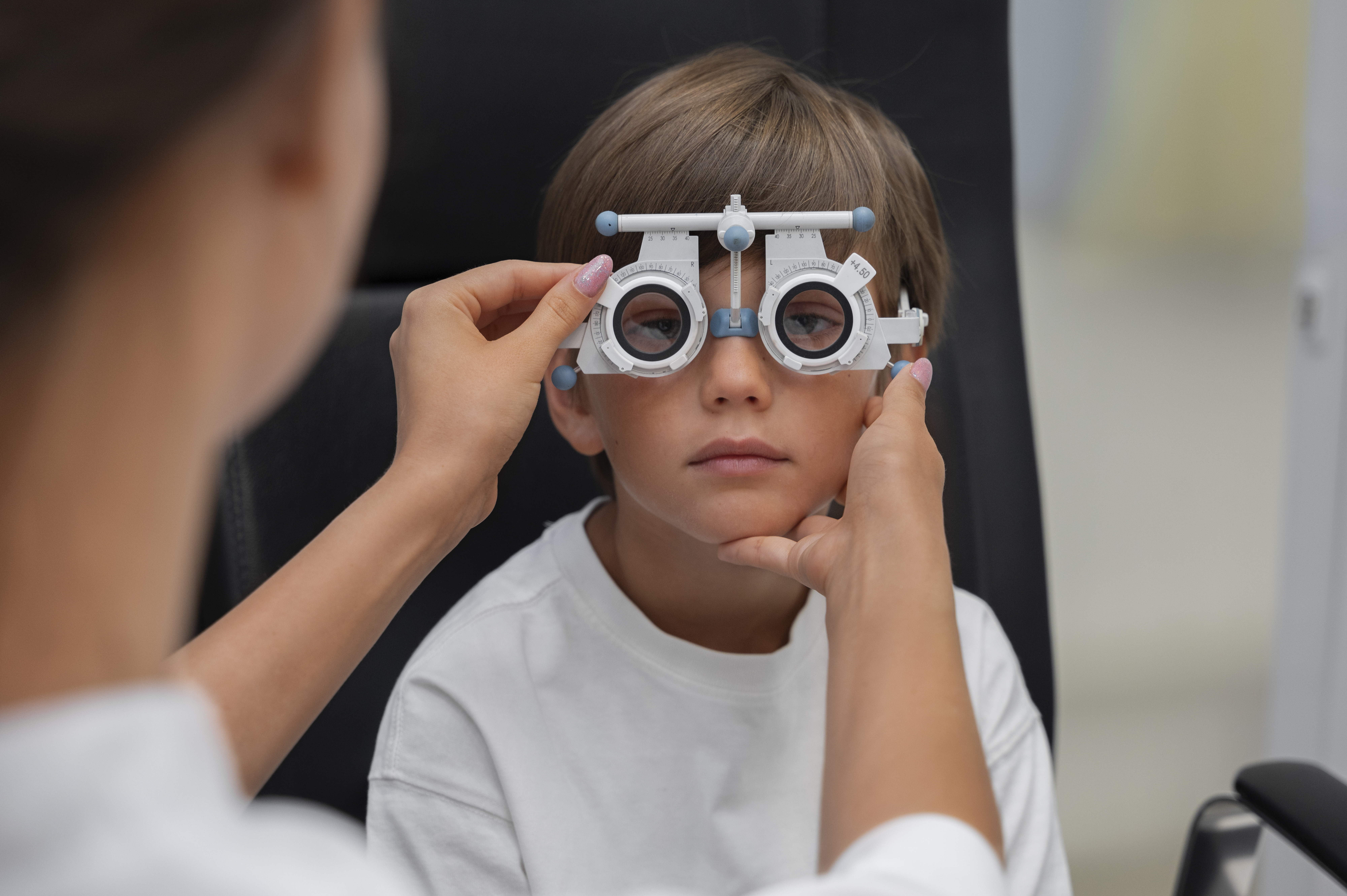 An optometrist performing an eye test on a young boy using a phoropter during a vision checkup